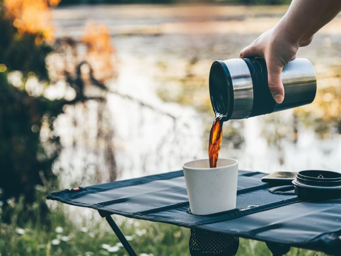 Person som njuter av en kaffe i naturen och samtidigt har en passiv inkomst.