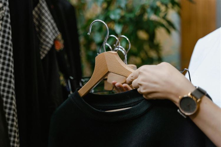 en person som hänger upp kläder på en galge i en butik.