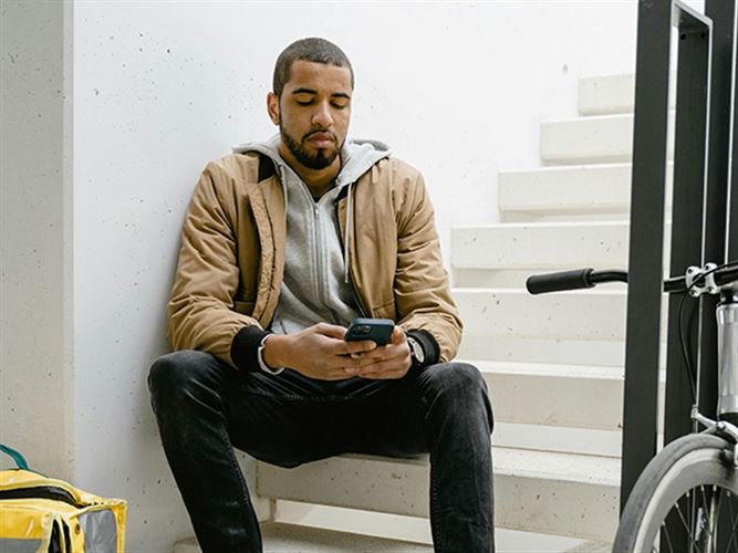 En kvinna sitter med ansiktet i sina händer framför en dator.