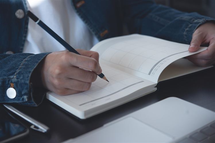 en hand som skriver i en bok