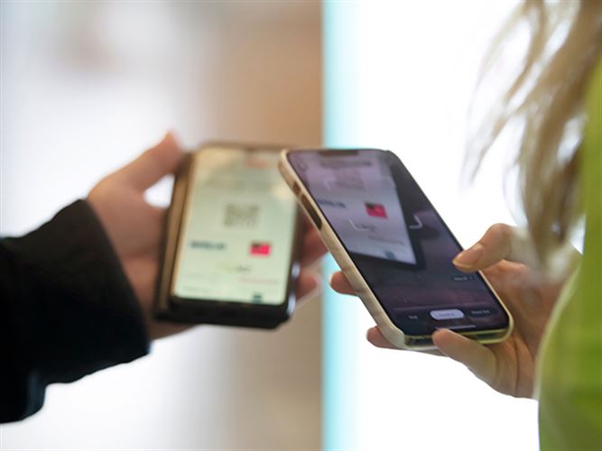 Två människor som håller i varsin smartphone. Bilden ska föreställa att skapa en app.