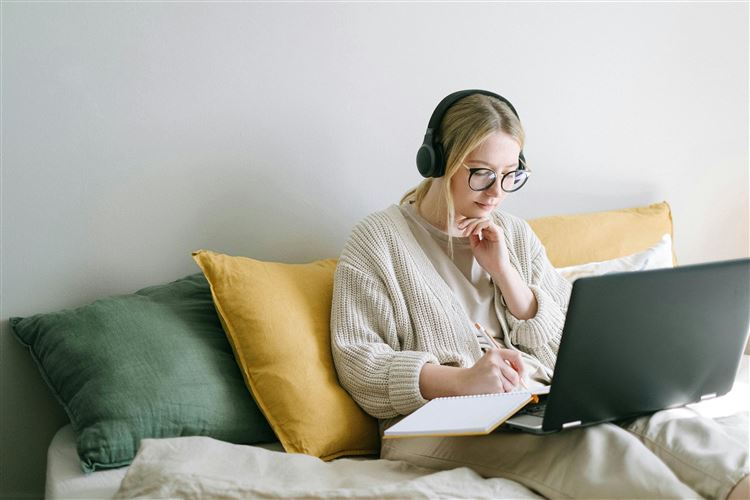 Kvinna sitter i en soffa framför en laptop för att fylla i K10-blanketten.