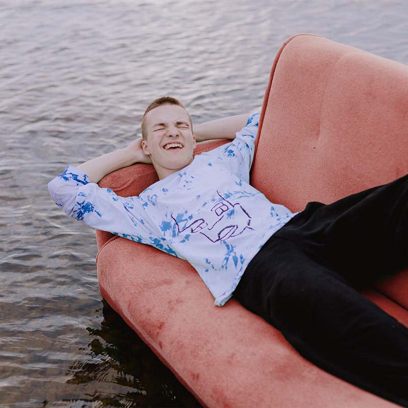 En ung glad kille som ligger i en uppblåsbar soffa ute på vattnet.