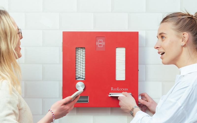 Två kvinnor och ett rött RedLocker skåp